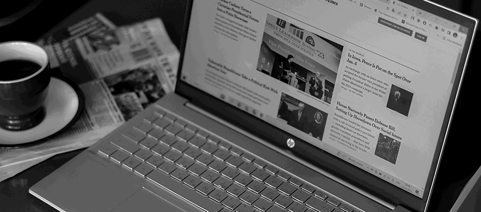 News website displayed on laptop with a cup of coffee next to it