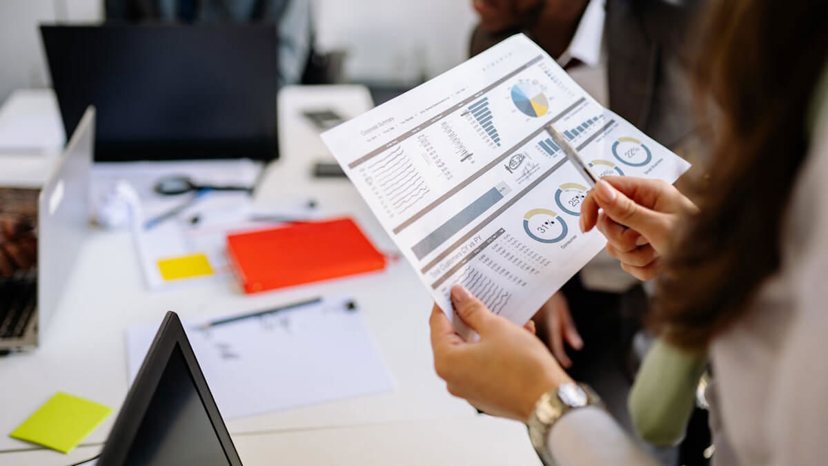  A female holding a pen and a sheet of paper with graphs