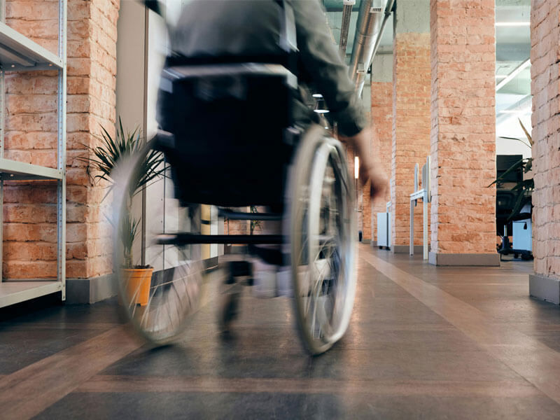 Person in wheelchair going down corridor