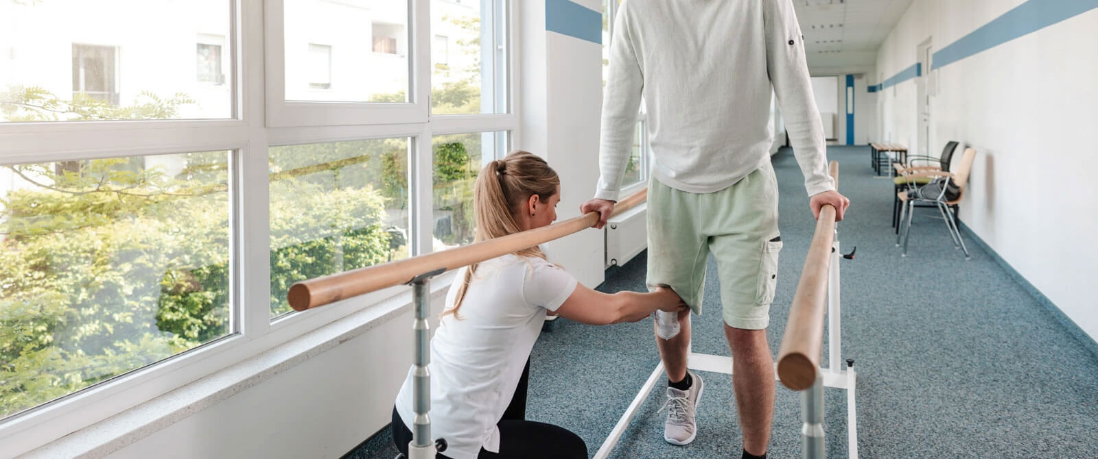 Physio helping a young man learn to work aided