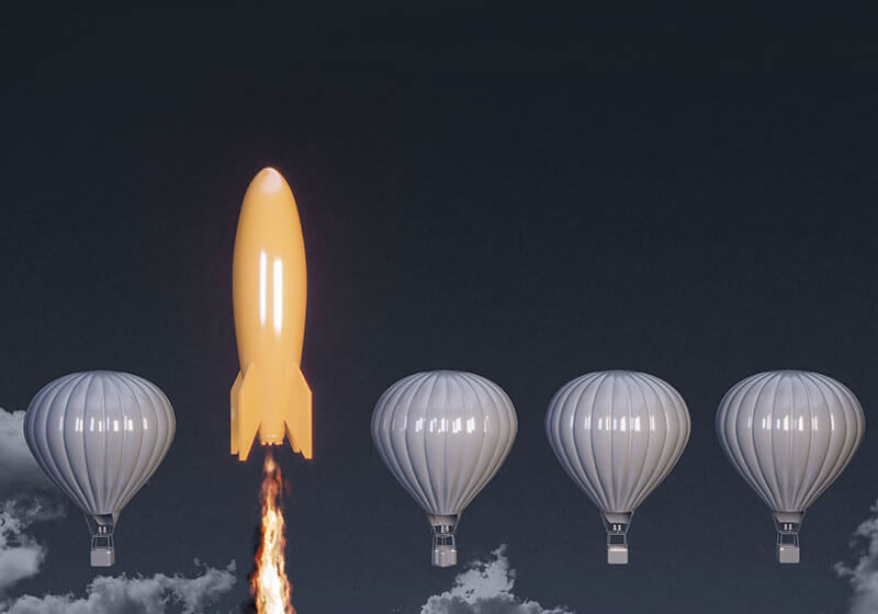 An orange rocket taking off next to three grey hot air balloons