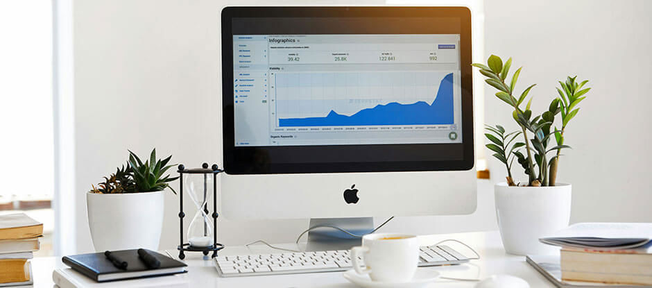 Computer on a desk showing a positive trend graph